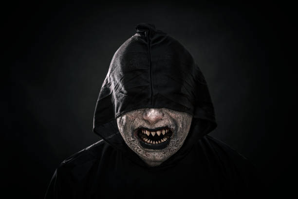 istock Scary figure in hooded cloak showing his sharp pointy teeth 1130509636