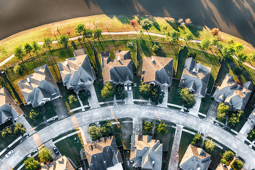 Aerial view looking directly down on a curve on a suburban street in a planned exclusive residential community in the Houston, Texas area.