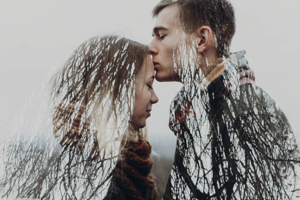 istock stylish hipster couple in double exposure with tree branches in park. sensual atmospheric moment with space for text. man kissing woman. creative unusual photo 1130515122
