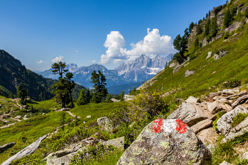 Hiking mark sign red white red painted on rock on mountain Reiteralm with distant view to mountain Dachstein in Austria