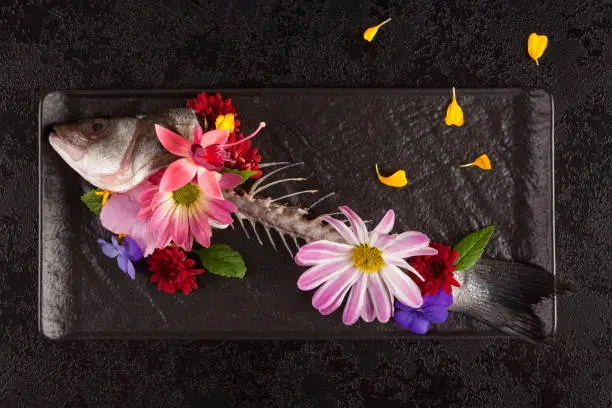 Photo of Skelet of fish with flowers from above.