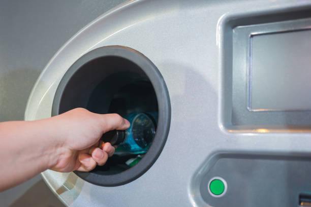 istock Reverse Vending Recycling Machine. Recycling machine that dispenses cash. Man hand puts plastic bottle to the machine 1130523340