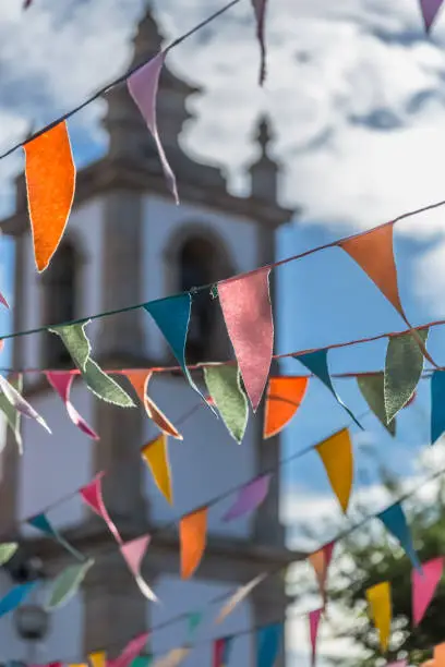 Photo of View of traditional decoration of religious festivals on the villages, with colored triangles of paper hanging in threads, church tower on background
