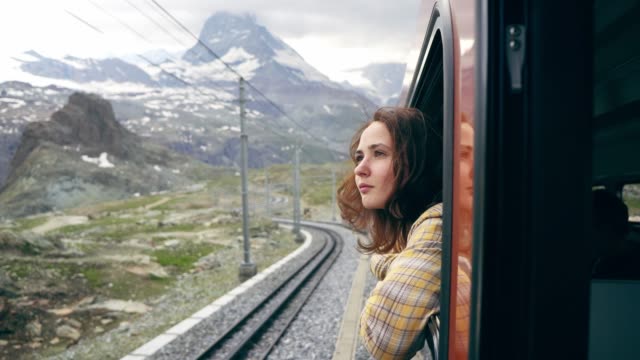Wanita Kaukasia muda melihat keluar jendela di kereta dekat Matterhorn