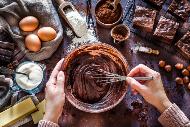 chocolate brownie preparation on kitchen table - mixing bowl imagens e fotografias de stock