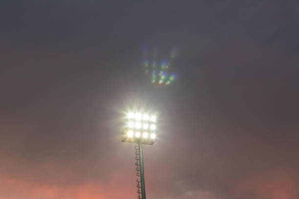large tall high outdoor stadium spotlights on rigid frame construction under natural sunlight. spotlights tower in the stadium twilight time
