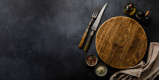istock Round wooden Cutting board and Spices for cooking on dark concrete backdrop Surface copy space for design text 1130531530