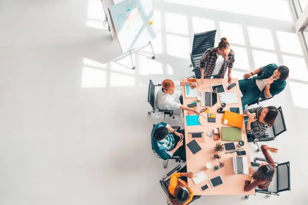 Photo of Multiethnic diverse group of business coworkers in team meeting discussion, top view modern office with copy space. Partnership professional teamwork, startup company, or project brainstorm concept