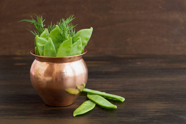 istock Young fresh green peas on wooden background. 1130535639