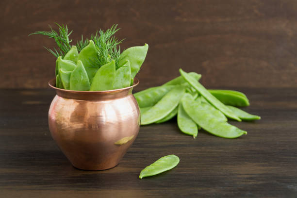 istock Young fresh green peas on wooden background. 1130535730