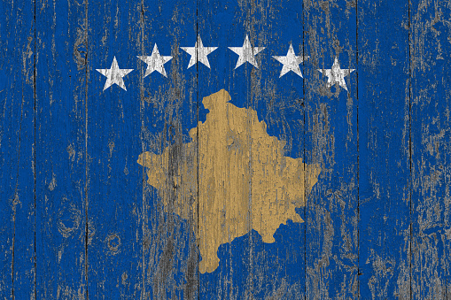 Flag of Kosovo painted on worn out wooden texture background.