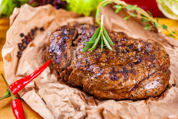 istock Grilled meat with spices and herbs  on wooden board 1130537270