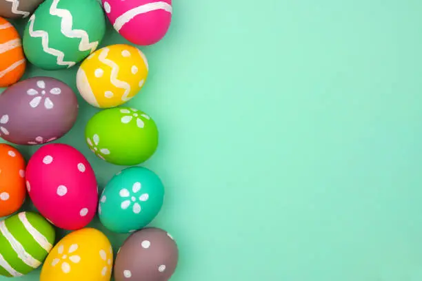 Colorful Easter Egg side border against a turquoise green background. Top view with copy space.