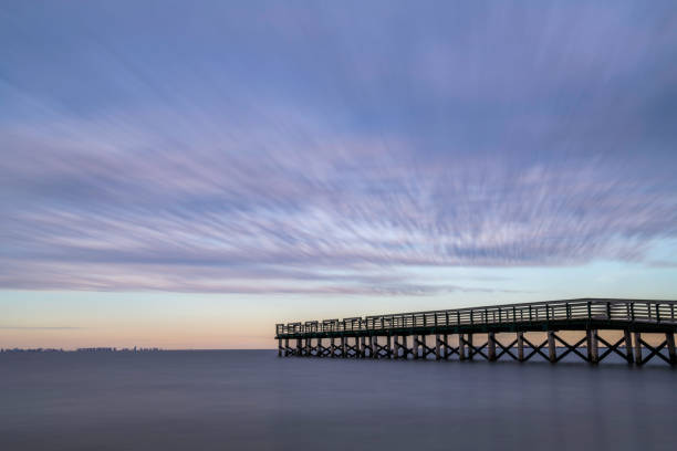 Dramatic beach scenery featuring stormy sky over the fishing pier at New Jersey shore. Shot using slow shutter speed