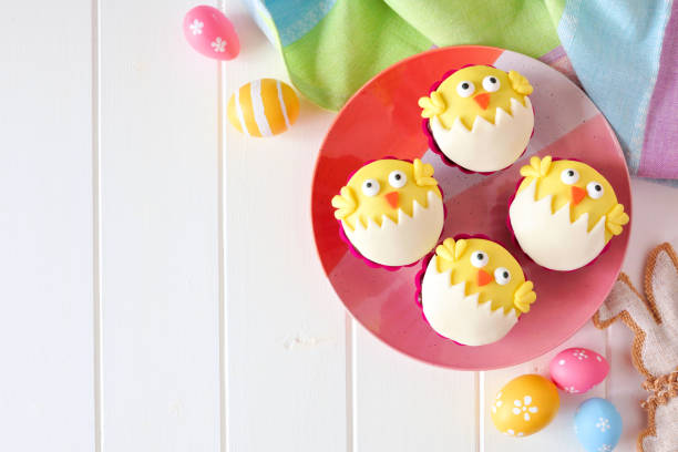 istock Hatching spring chick cupcakes, flay lay, corner border against white wood 1130539124