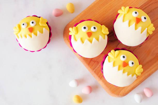 istock Hatching spring chick cupcakes on a wood platter, top view over marble 1130539813