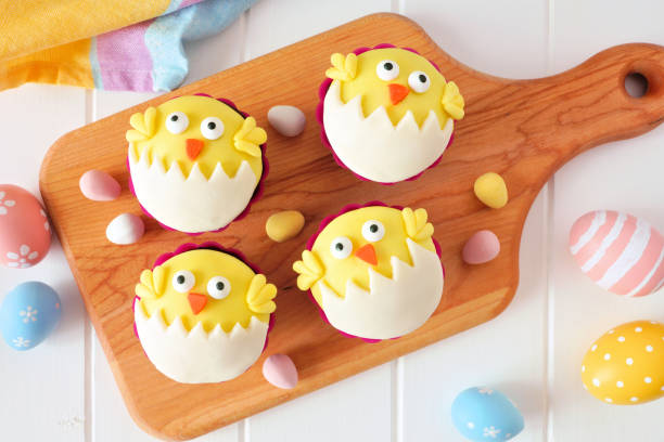 istock Hatching spring chick cupcakes on a wood paddle board over white wood 1130539924
