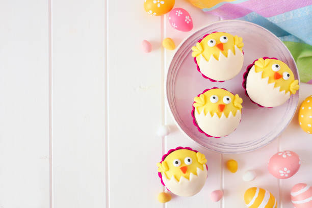 istock Hatching spring chick cupcakes, above view side border over white wood 1130540025