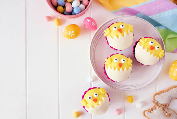 istock Hatching spring chick cupcakes, above view border over white wood 1130540093