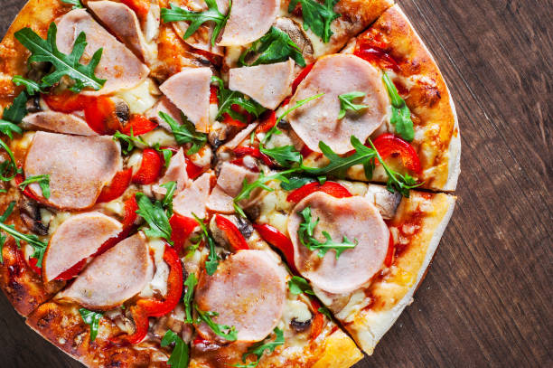 istock Pizza with Mozzarella cheese, mushrooms, ham, tomato sauce, pepper, Spices and Fresh arugula. Italian pizza on wooden table background 1130540537