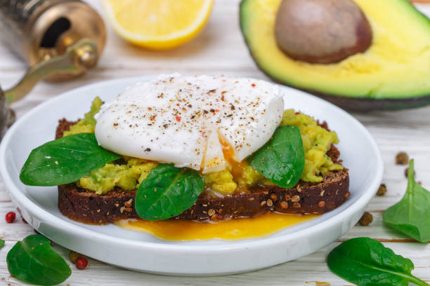 istock Rye Bread Toast with coriander, Poached Egg with Green Salad spinach , Avocado (guacamole), lemon and spices. Gourmet sandwich. Healthy Breakfast. Selective focus 1130541435