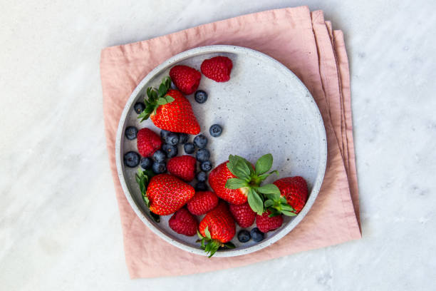 istock Mixed berries in conrete plate on marble background with empty plate and copy space 1130544702