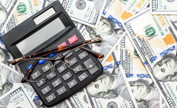 istock Calculator with glasses on background of dollar bills. Top view. Space for text. 1130544735