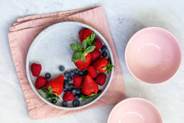 istock Mixed berries in conrete plate on marble background with empty plate and copy space 1130544843