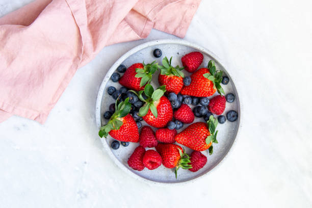 istock Mixed berries in conrete plate on marble background with empty plate and copy space 1130544922