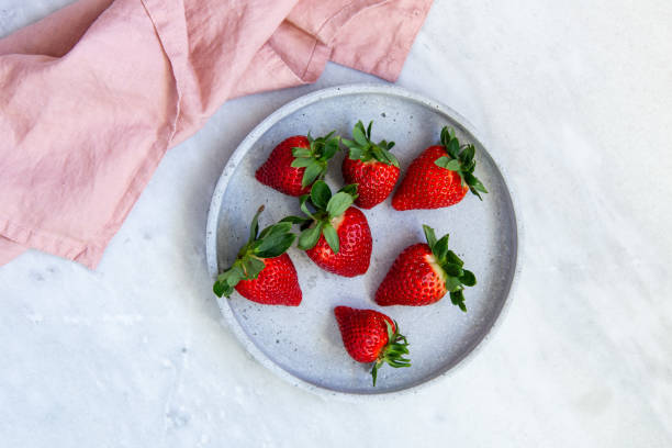 Delicious ripe strawberries in rustic bowl on marble background. Directly above view stock photo