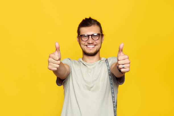 istock Attractive caucasian man smiling and showing thumb up gesture with both hands over yellow background and looking at camera. 1130545006