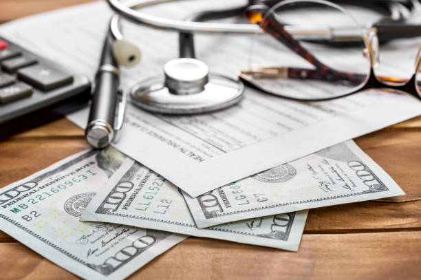 Health insurance claim form with money, calculator and stethoscope on the table. stock photo