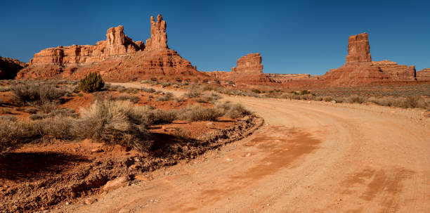 istock Dirt road leads through red rock monuments in a valley Utah 1130545571