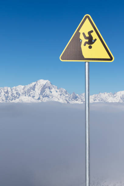 Yellow warning sign of possible fall from a cliff. Dangerous extreme sports concept. The highest European mountain Mont Blanc in background. Yellow warning sign of possible fall from a cliff. Dangerous extreme sports concept. The highest European mountain Mont Blanc in background. la plagne photos stock pictures, royalty-free photos & images