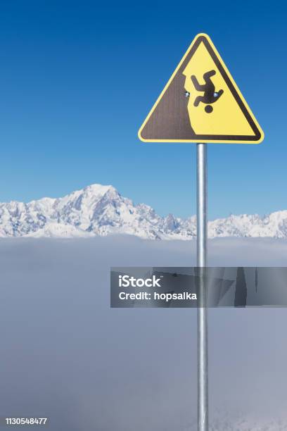 Yellow Warning Sign Of Possible Fall From A Cliff Dangerous Extreme Sports Concept The Highest European Mountain Mont Blanc In Background Stock Photo - Download Image Now