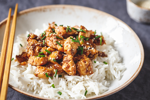 Sesame chicken pieces with rice on a ceramic plate. Chinese traditional dish.
