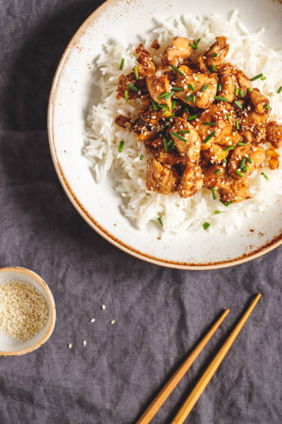 istock Top view on sesame chicken pieces with rice on a ceramic plate. Chinese traditional dish. Copy space. 1130549576