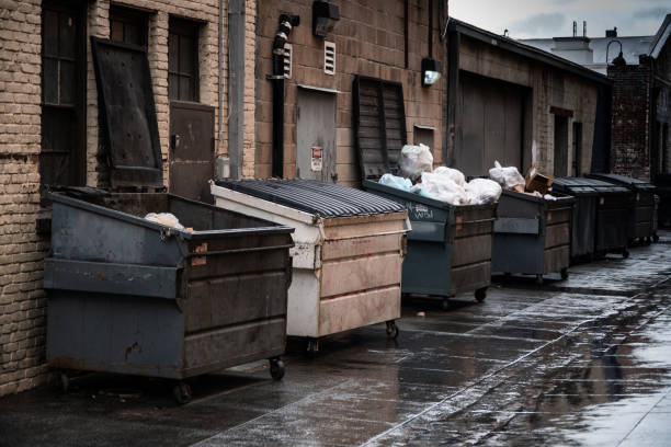 Trash Dumpsters Alley way lined with opened and closed industrial sized trash dumpsters. industrial garbage bin photos stock pictures, royalty-free photos & images