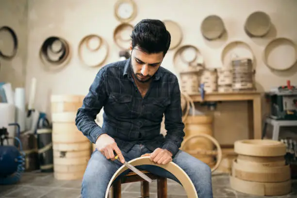 Turkish craftsman carving traditional wood drum instrument