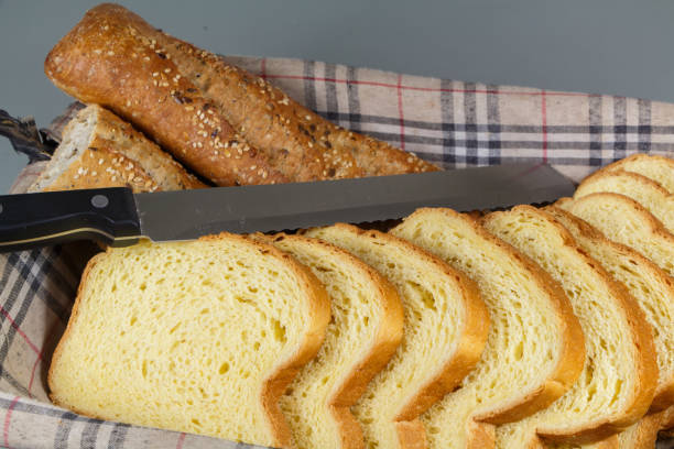 Pieces of traditional french baguette bread, slices of brioche and knife in a breadbasket