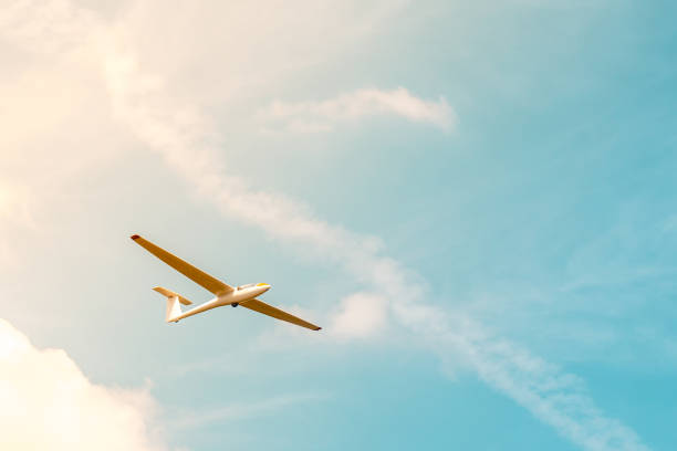 planeur de vol contre le ciel bleu avec des nuages et du soleil - flying air vehicle performance airshow photos et images de collection