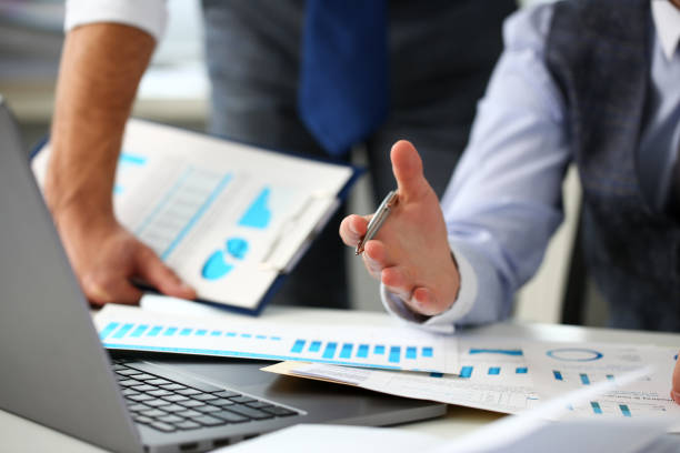 istock Group of businessmen point arm with silver pen at laptop pc 1130554545