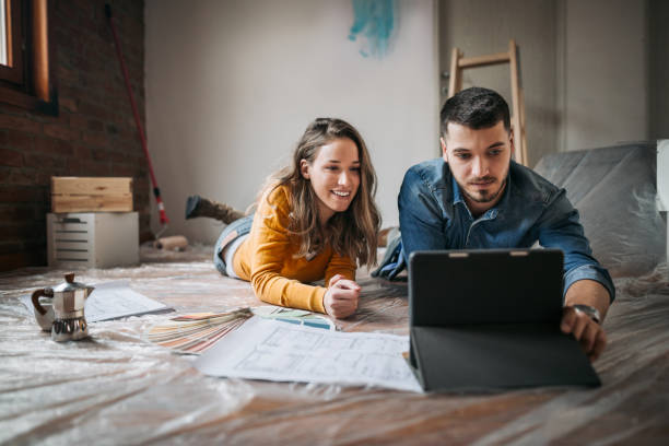 Happy couple lying down in new home Young couple taking a break from painting and restoring their apartment by lying on the floor restoring home improvement house home interior stock pictures, royalty-free photos & images