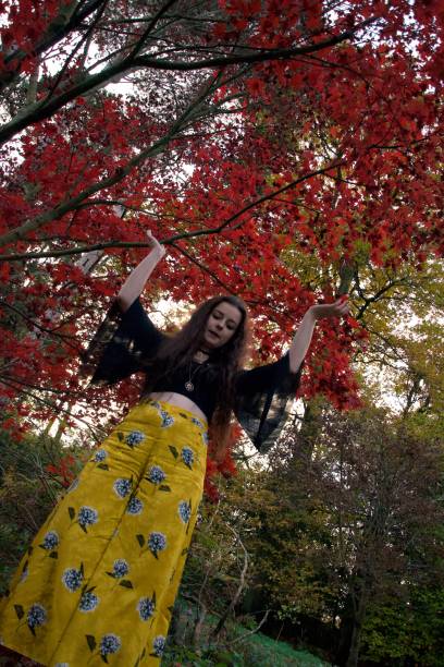 istock Fashionably dressed lady dancing under falling red autumn leaves 1130557190