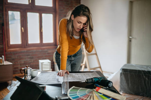 Business woman making important business call Young female apartmant owner making important phone call while looking at the renovation plans restoring home improvement house home interior stock pictures, royalty-free photos & images