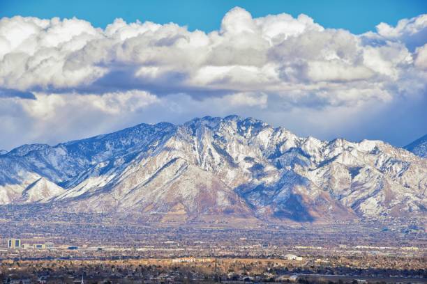 Winter Panoramic view of Snow capped Wasatch Front Rocky Mountains, Great Salt Lake Valley and Cloudscape. Utah, USA. stock photo
