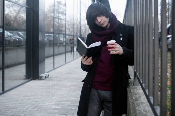 learning student at street The trendy student is learning, studying, reading a book and drinking coffee at the street. emo boy stock pictures, royalty-free photos & images