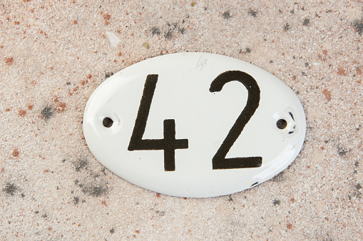 Old house number sign #42 on concrete background. Copy space for text