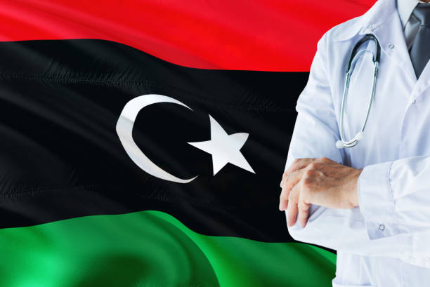 Libyan Doctor standing with stethoscope on Libya flag background. National healthcare system concept, medical theme. libio médico con estetoscopio sobre fondo de bandera de libia. concepto de sistema nacional de salud, tema médico. libio médico con estetoscopio sobre fondo de bandera de libia. concepto de sistema nacional de salud, tema médico. libio médico permanen
