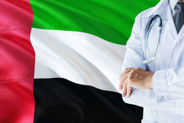 Emirian Doctor standing with stethoscope on United Arab Emirates flag background. National healthcare system concept, medical theme. emirian médico con estetoscopio sobre fondo de bandera de emiratos Árabes unidos. concepto de sistema nacional de salud, tema médico. emirian médico con estetoscopio sobre fondo de bandera de emiratos Árabes unidos. concepto de sistema nacional de sal